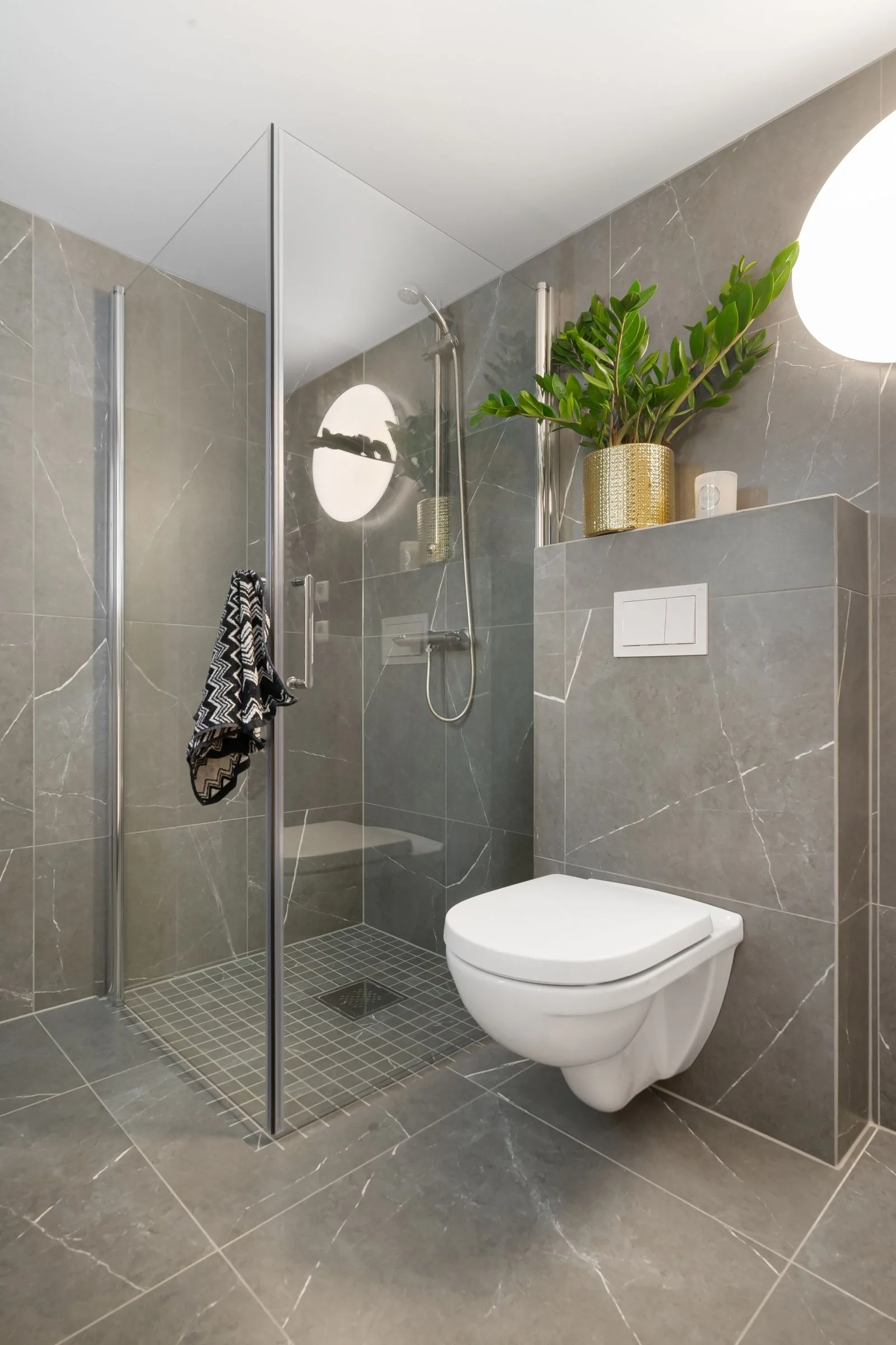 Casa de banho de nível médio: grés porcelânico cinzento do chão ao teto, sanita suspensa, resguardo de vidro fixo, coluna de duche cromada