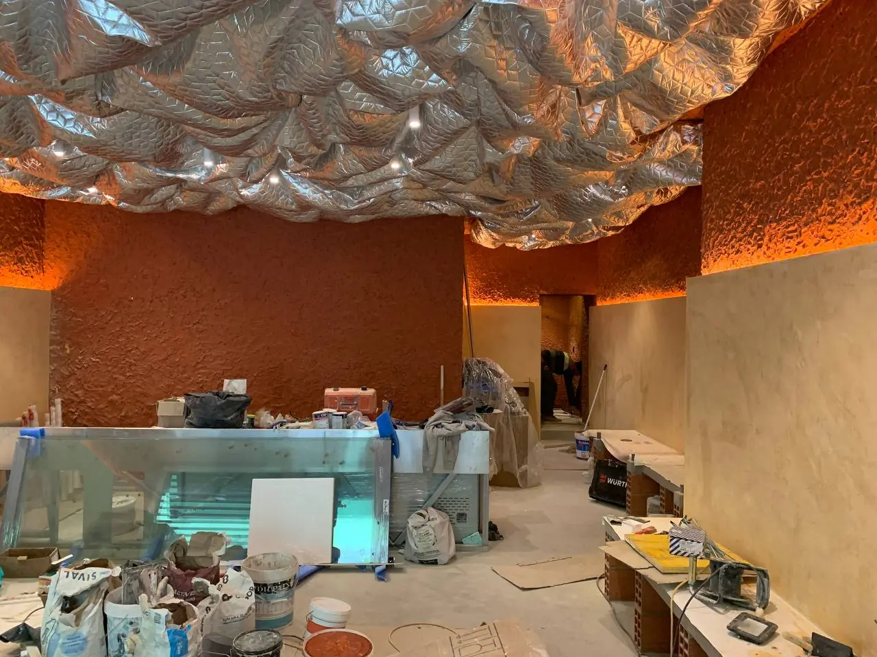 A meio da obra: estuque terracota e teto metálico a serem aplicados, com entulho ainda no chão