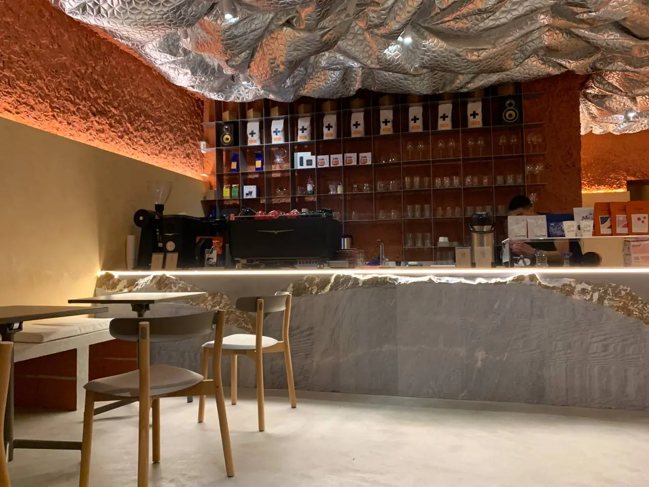 Balcão do café concluído: estuque terracota com iluminação embutida, balcão em pedra natural, bar em funcionamento