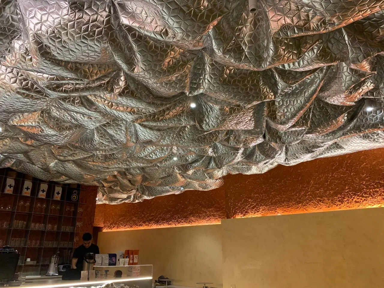 Zona de mesas do café concluído, cadeiras em madeira, teto metálico por cima