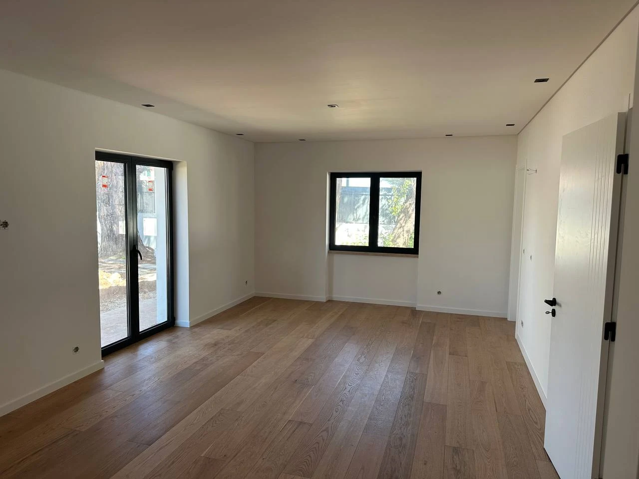 Sala de apartamento acabada de entregar, vazia, com pavimento de madeira novo e paredes pintadas