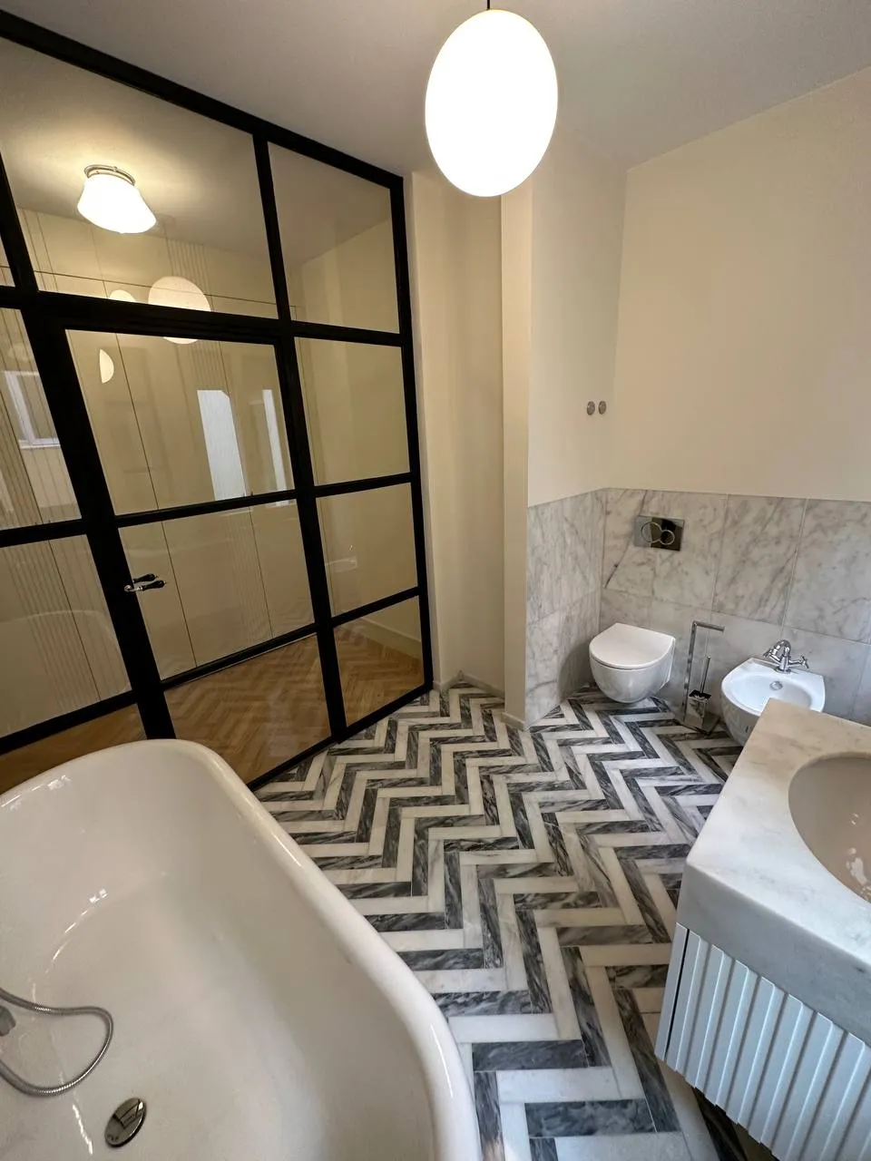 Banheira de pés vista através da porta envidraçada de perfil preto