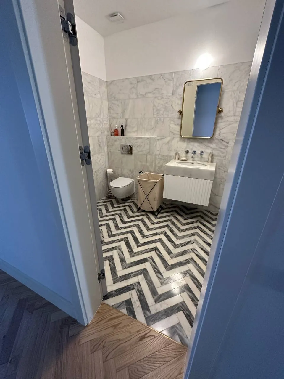Casa de banho vista da porta azul, com chão em mármore ao espinha