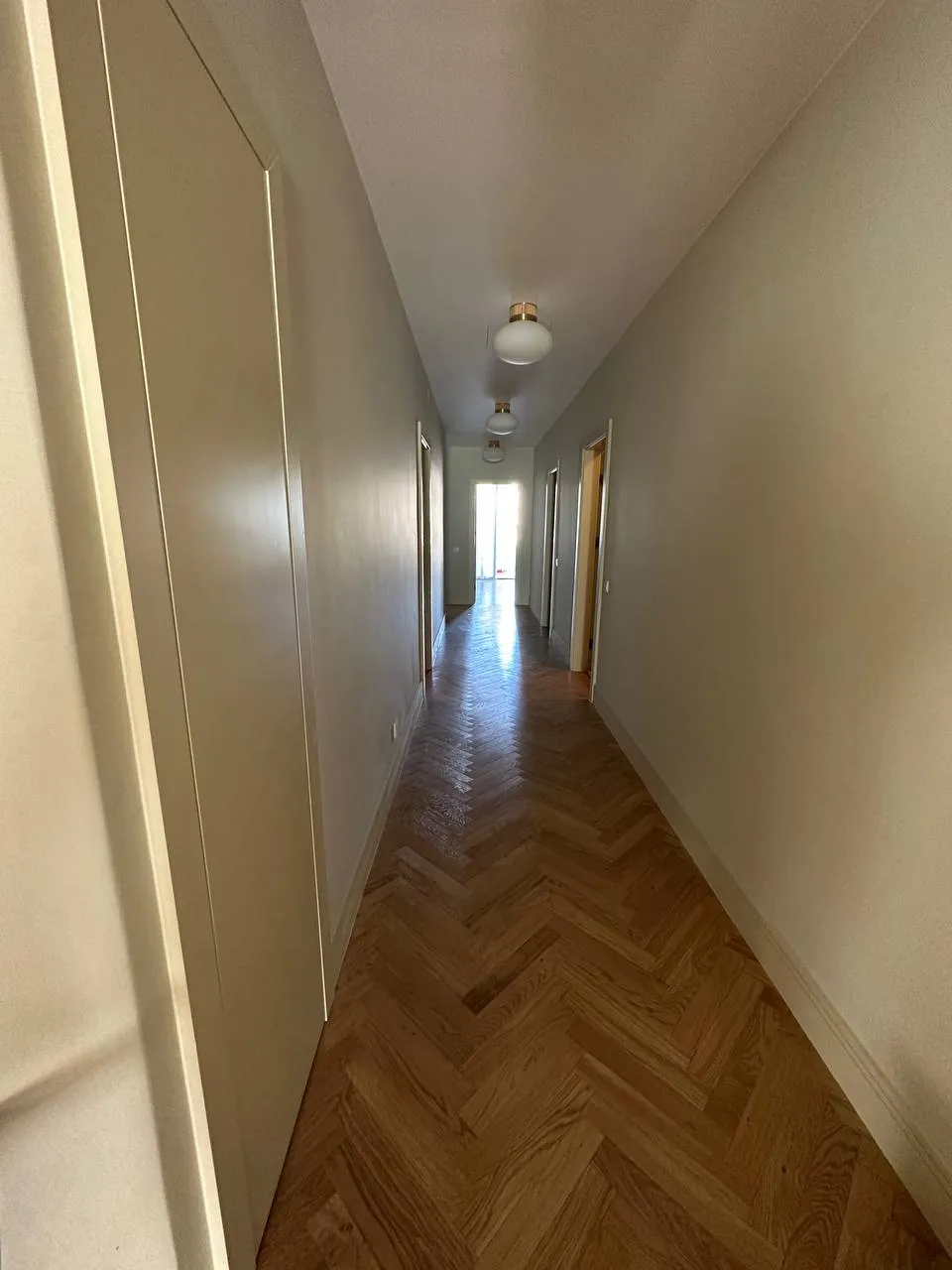 Corredor com parquet em espinha e portas lacadas de branco
