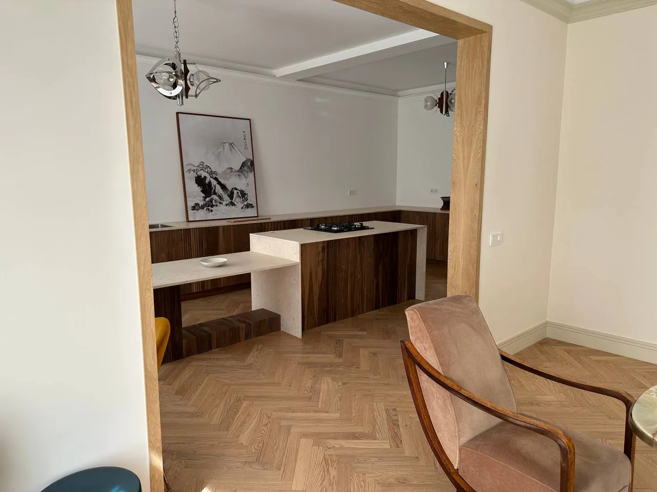 Cozinha vista através do portal em carvalho, com poltrona de meados do século em primeiro plano
