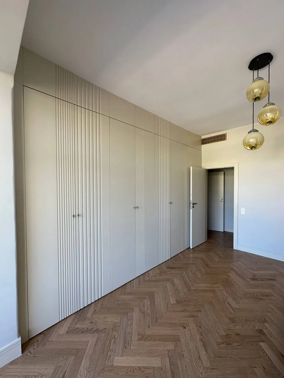 Quarto com roupeiro de porta canelada branca e parquet em espinha