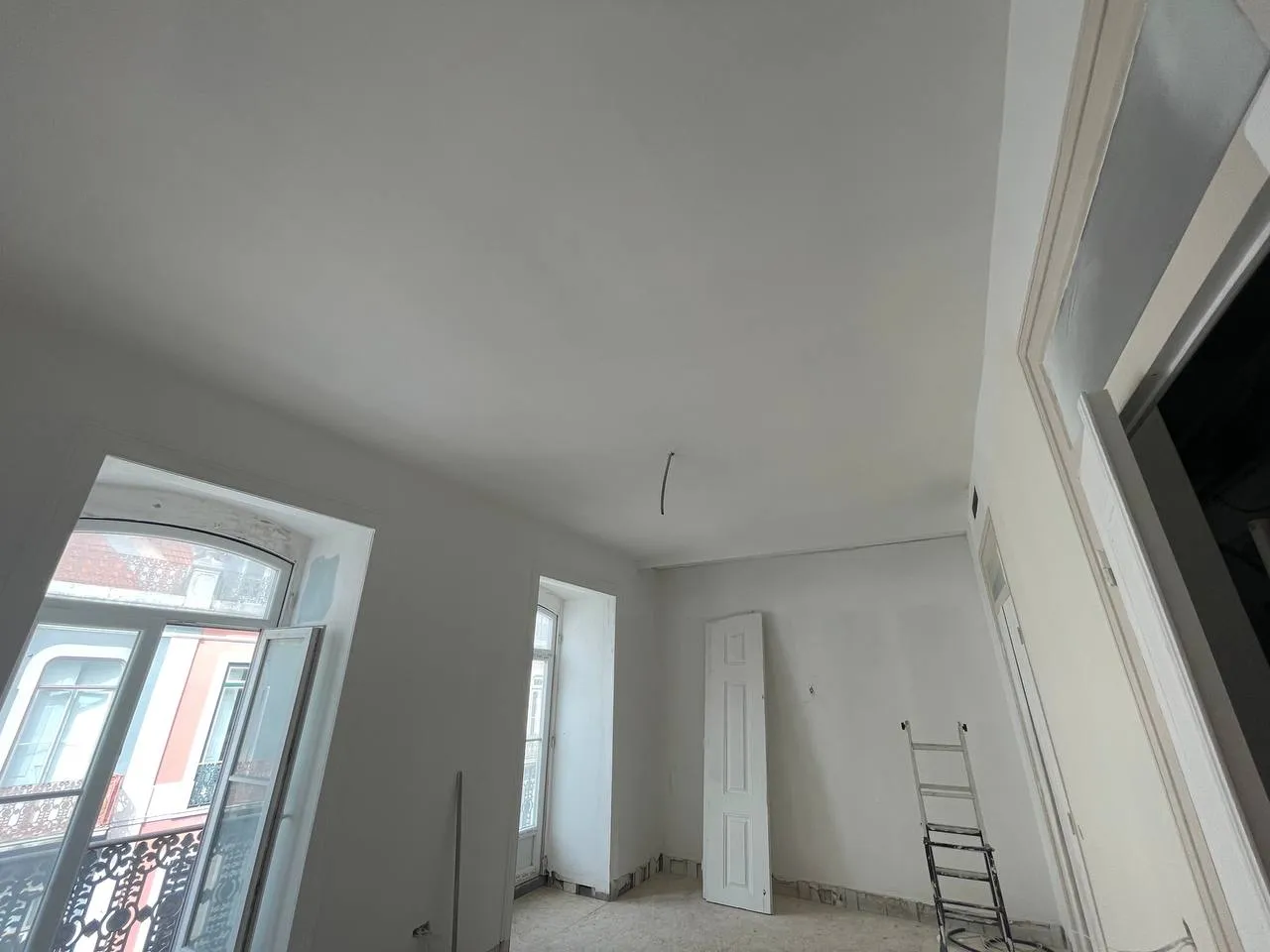 Sala em obra com paredes já lisas e janelas de sacada
