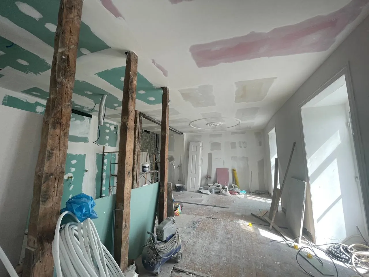 Sala em obra com vigas de madeira expostas e material de estaleiro
