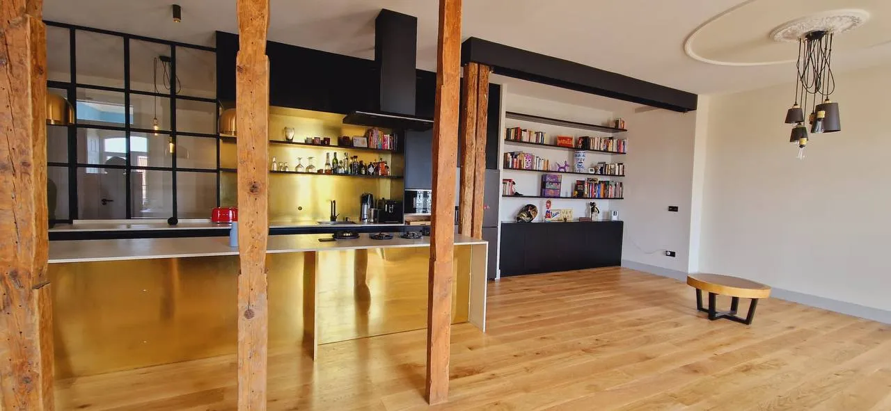 A mesma cozinha vista do lado da sala, com estante integrada e candeeiros suspensos