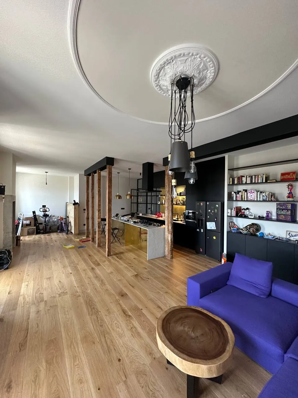 O mesmo apartamento concluído: sala com colunas de madeira restauradas, sancas originais e estante integrada